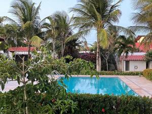a swimming pool in front of a resort with palm trees at Praia Marina Suite - Morro Branco in Beberibe