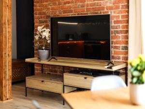 a living room with a television on a brick wall at Brick and Wood Apartments in Bydgoszcz