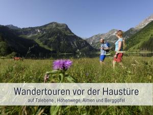 two children in a field with mountains in the background at Apartments Tannheim - Ruhige Apartments mit Infrarotsauna & Sommerbergbahnen inklusive in Tannheim