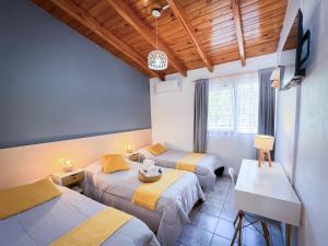 a room with two beds and a desk and a tv at Hotel Alta Mendoza in Mendoza