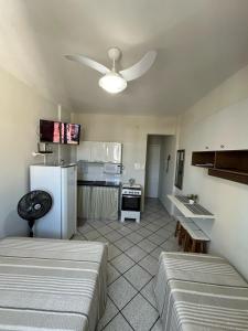 a kitchen with two beds and a white refrigerator at KITNET ACONCHEGANTE A 3 MINUTOS DA PRAIA in Guarapari