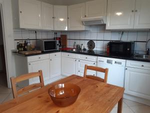 een keuken met witte kasten en een houten tafel bij Spacieux et lumineux T5 avec 4 chambres, au centre-ville de Mulhouse, grand balcon, grand écran plat in Mulhouse
