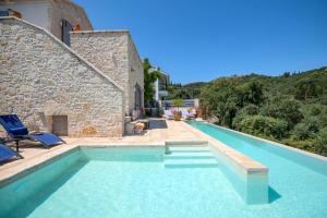 a swimming pool in front of a stone house at Bee Tree Villa in Corfu
