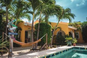 a yellow house with palm trees and a swimming pool at Casa di Mario in Kralendijk
