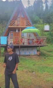 吉布Valley top cottage的站在房子前面的男人,拿着一把伞