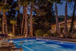 a swimming pool with palm trees next to a house at Villa Palmera in Olivella