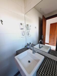 a bathroom with a sink and a mirror at Suíte Delicada Centro Búzios in Búzios