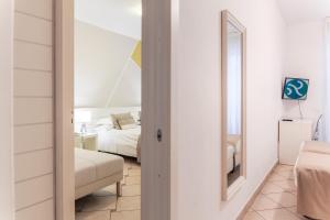 a white bedroom with a bed and a mirror at Hotel Rivage in Sorrento