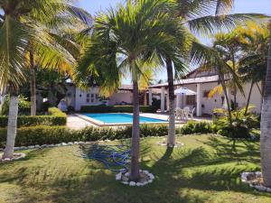a villa with a swimming pool and palm trees at Praia Marina Suite - Morro Branco in Beberibe