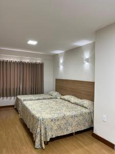 a bedroom with two beds and a window at Hotel Nascentes da Serra in Poços de Caldas