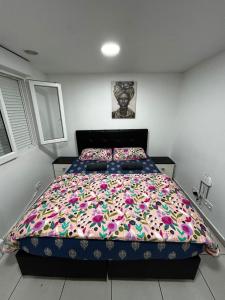 a bedroom with a large bed with a colorful comforter at Petit paradis pour 2 personnes in Garges-lès-Gonesse