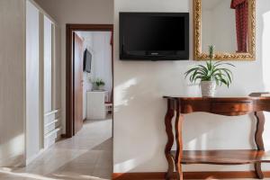 a living room with a table and a tv on a wall at Hotel Du Soleil in Rimini