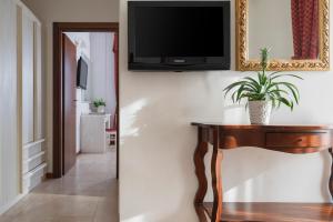a living room with a table and a television on a wall at Hotel Du Soleil in Rimini
