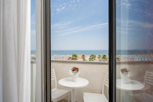 a room with a view of the beach from a balcony at Hotel Du Soleil in Rimini