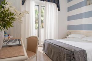 a bedroom with a bed and a table and a window at Hotel Du Soleil in Rimini