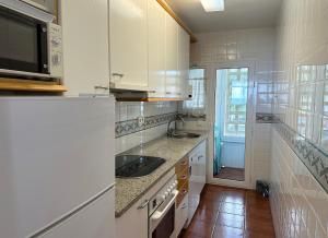 eine weiße Küche mit Spüle und Mikrowelle in der Unterkunft Paraiso Frente al Mar - 332 in Pals