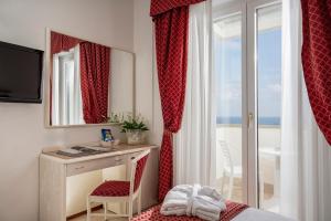 a hotel room with a desk and a mirror at Hotel Du Soleil in Rimini