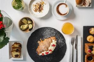 a table with a black plate of food and desserts at Hotel Du Soleil in Rimini