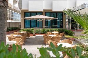 a patio with tables and chairs and an umbrella at Hotel Du Soleil in Rimini