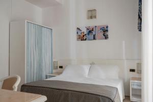 a bedroom with a white bed and a table at Hotel Du Soleil in Rimini
