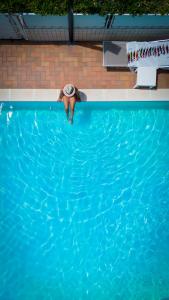 a man in a hat standing in a swimming pool at Hotel Du Soleil in Rimini