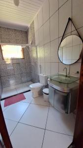 une salle de bain avec toilettes, lavabo et miroir dans l'établissement Casa de campo Sanloá, à Parati