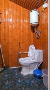 a bathroom with a toilet in a wooden wall at TREE HOUSE BY THE CITY ESCAPE in Shimla