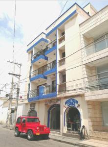 a red jeep parked in front of a building at María Hosting !!! in Santa Marta