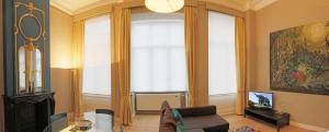 uma sala de estar com um sofá, uma mesa e janelas em Aparthotel Liège em Liège
