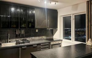 Una cocina con gabinetes negros y vista a la ciudad. en 3 Bedroom Nice Apartment In Trondheim, en Trondheim
