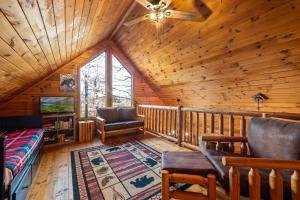 Una sala de estar tipo cabaña de troncos con ventilador de techo. en Bearolina On My Mind, en Pigeon Forge
