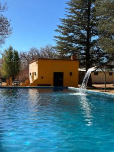 a pool with a water fountain in front of a building at Posada San Eduardo in Barreal