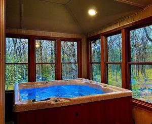 a large bath tub in a room with windows at Woodland Cabin Getaway in Greentown