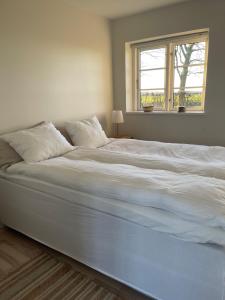 a large white bed in a bedroom with a window at Gatekeepers house in Søllested
