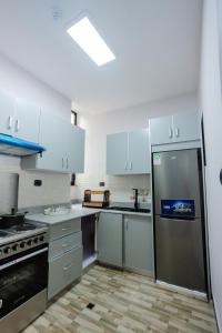 Una cocina con gabinetes blancos y un refrigerador de acero inoxidable. en Amnen Apartments, en Addis Ababa