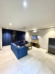 a living room with a blue couch and a flat screen tv at Sense luxury - 2 bed Apartment in Islamabad