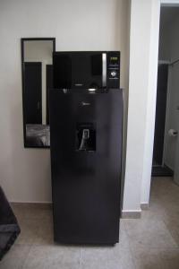 a black refrigerator with a microwave on top of it at Casa Creunza de Mar in Playa del Carmen