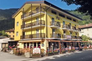 ein großes gelbes Gebäude mit Balkonen auf einer Straße in der Unterkunft Hotel Sport in Ledro