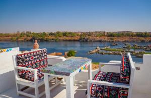 a table and chairs on a balcony with a view of a river at Kulaih nubian guest house in Aswan