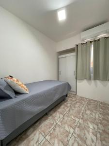 une chambre avec un lit et un sol carrelé dans l'établissement Apartamento em Maceió, à Maceió