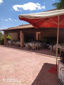 a restaurant with white tables and a red umbrella at Finca La Vega Bul in Estremera