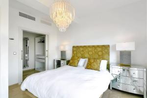 a white bedroom with a large bed and a chandelier at Villa Jacqueline in San Roque in La Alcaidesa +24 photos