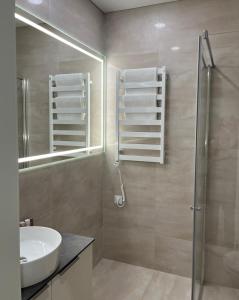 un bagno con lavandino, doccia e specchio di Maironio apartamentai a Kaunas