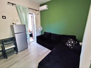 a living room with a black couch and a green wall at Pool me up 22 apartment in Megali Ammos