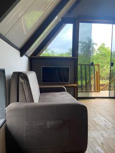 a living room with a couch and a flat screen tv at Cabanas Sudarê na Praia do Rosa in Imbituba