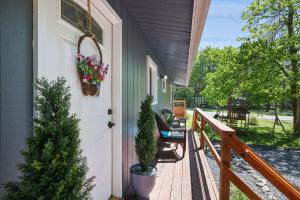 uma varanda de uma casa com uma árvore de natal e uma porta em COZY COTTAGE Spacious 4Bdrm 2Bth, Hot Tub, Game Movie Room, Firepit, Arcades, Backyard Playground, 2 Min Walk To Pool, Lake, Beach, Basketball, Minigolf and Tennis em Tobyhanna