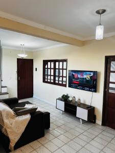 a living room with a couch and a tv on the wall at Apto no centro com 3 quartos in Ilhéus