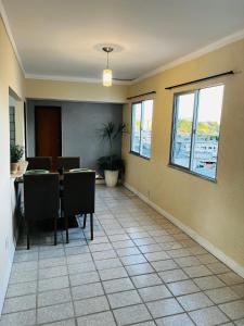 a dining room with a table and chairs and windows at Apto no centro com 3 quartos in Ilhéus
