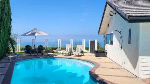 een zwembad met stoelen en een parasol naast een gebouw bij Ocean Views Beach House - 40 PCT Off Monthly in San Clemente
