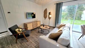 Una sala de estar con un sofá y una ventana grande. en Résidence Au Cœur de Soi, en Jonzac